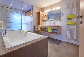 A modern bathroom with a large bathtub, a vanity with a mirror, and a towel rack.