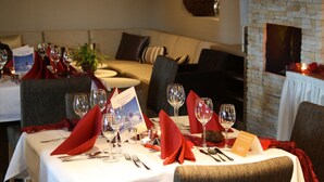 Une table à manger dressée avec des verres à vin, des serviettes rouges et un menu.