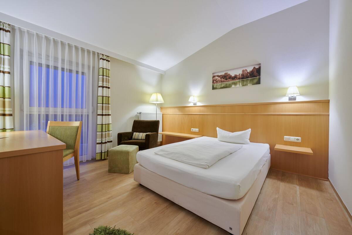 Une chambre d’hôtel avec un grand lit, un bureau, une chaise et une petite table.
