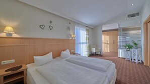 Une chambre d’hôtel avec deux lits, un bureau, une chaise et une petite table agrémentée de plantes.