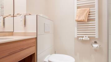 A modern bathroom with a wooden vanity, a toilet, a towel rack, and a mirror.