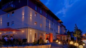 Un hôtel à plusieurs étages doté d’une terrasse et de fenêtres illuminées.