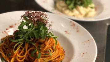 A plate of spaghetti with a garnish of greens and red seasoning.