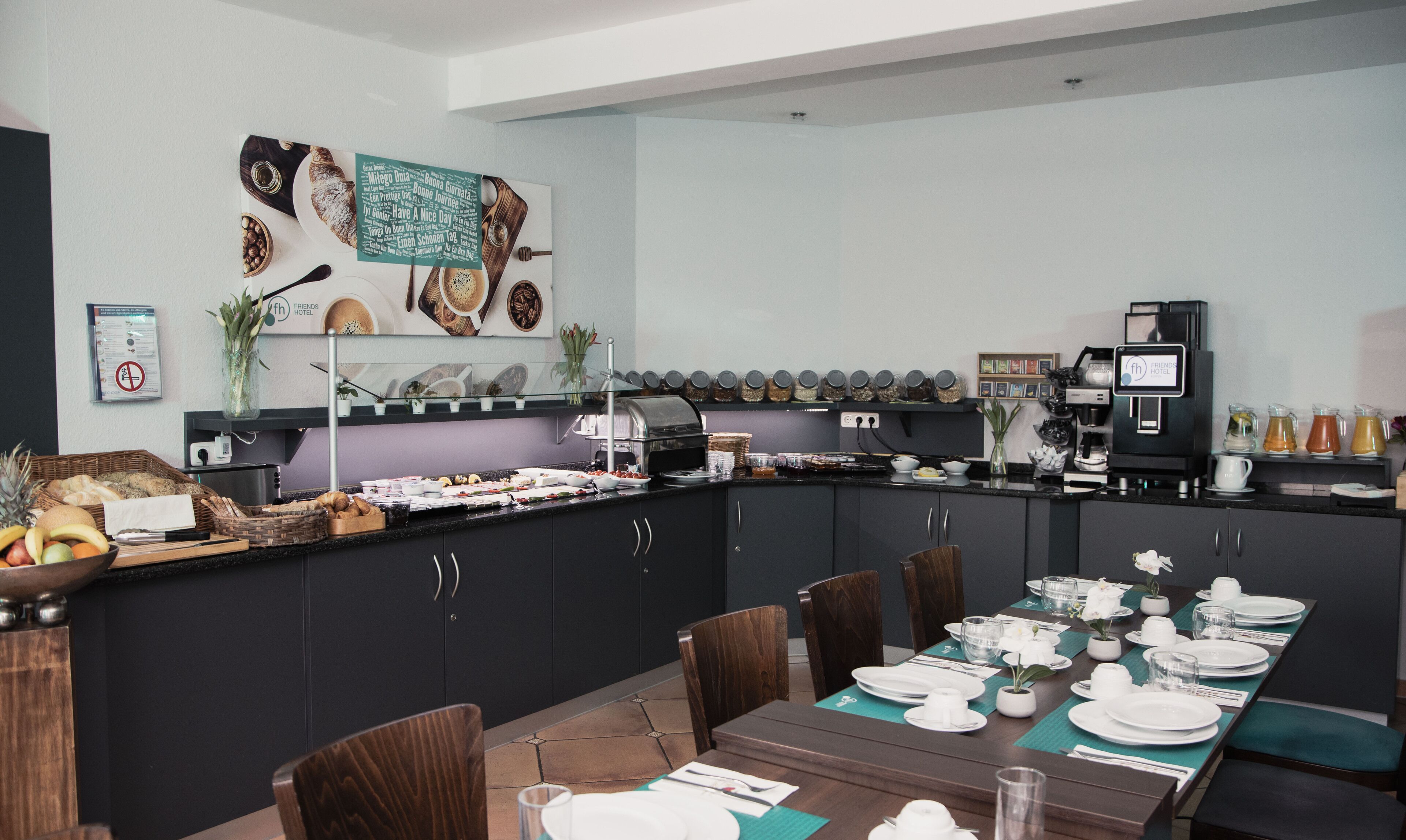 A breakfast buffet setup with a coffee machine, various food items, and a neatly arranged dining table with chairs.