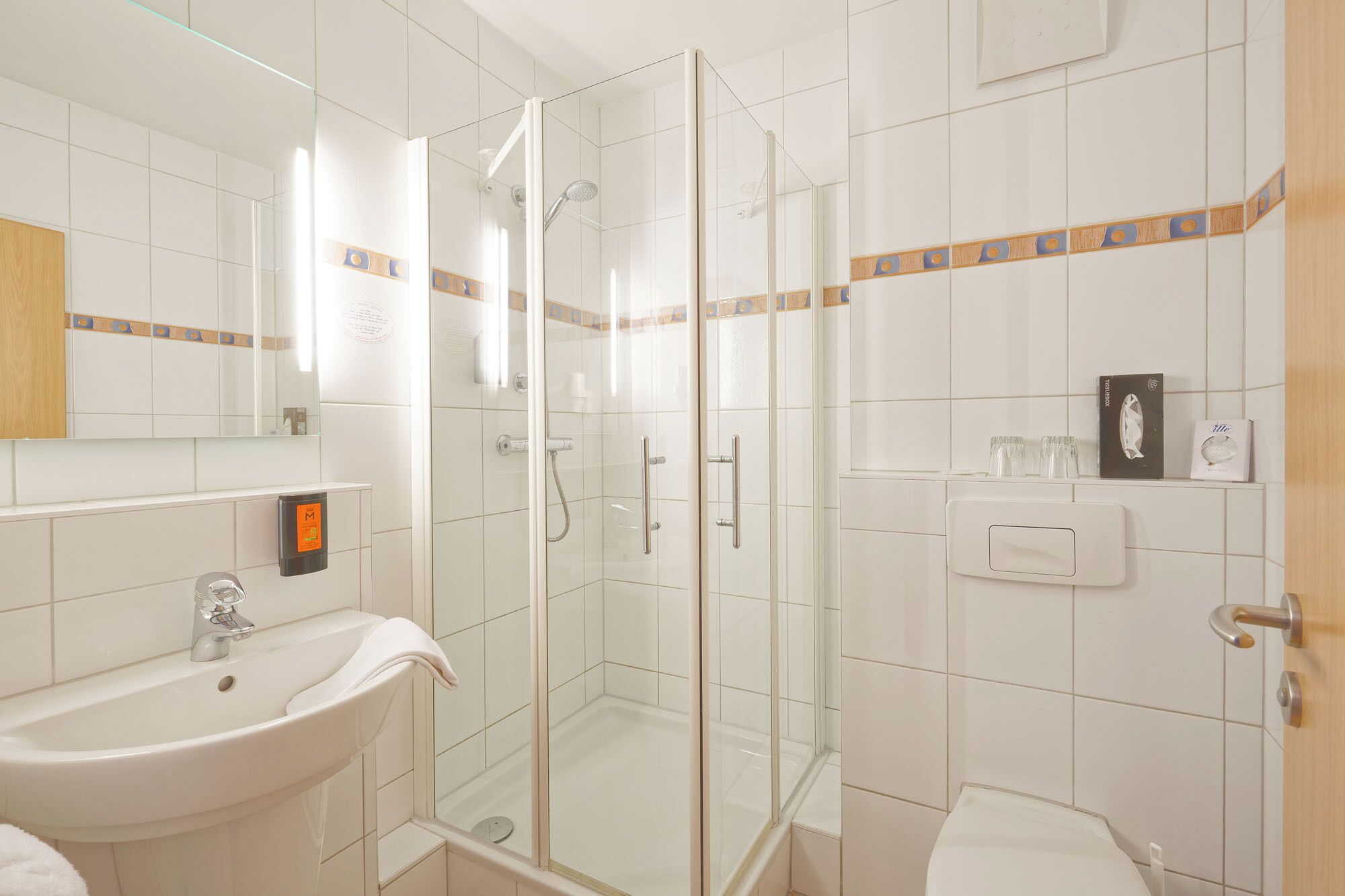 A bathroom with a glass-enclosed shower, a sink, and a toilet.