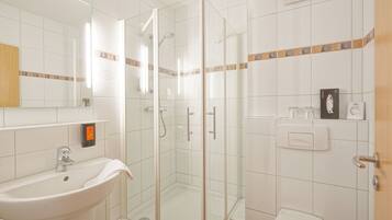 A bathroom with a glass-enclosed shower, a sink, and a toilet.