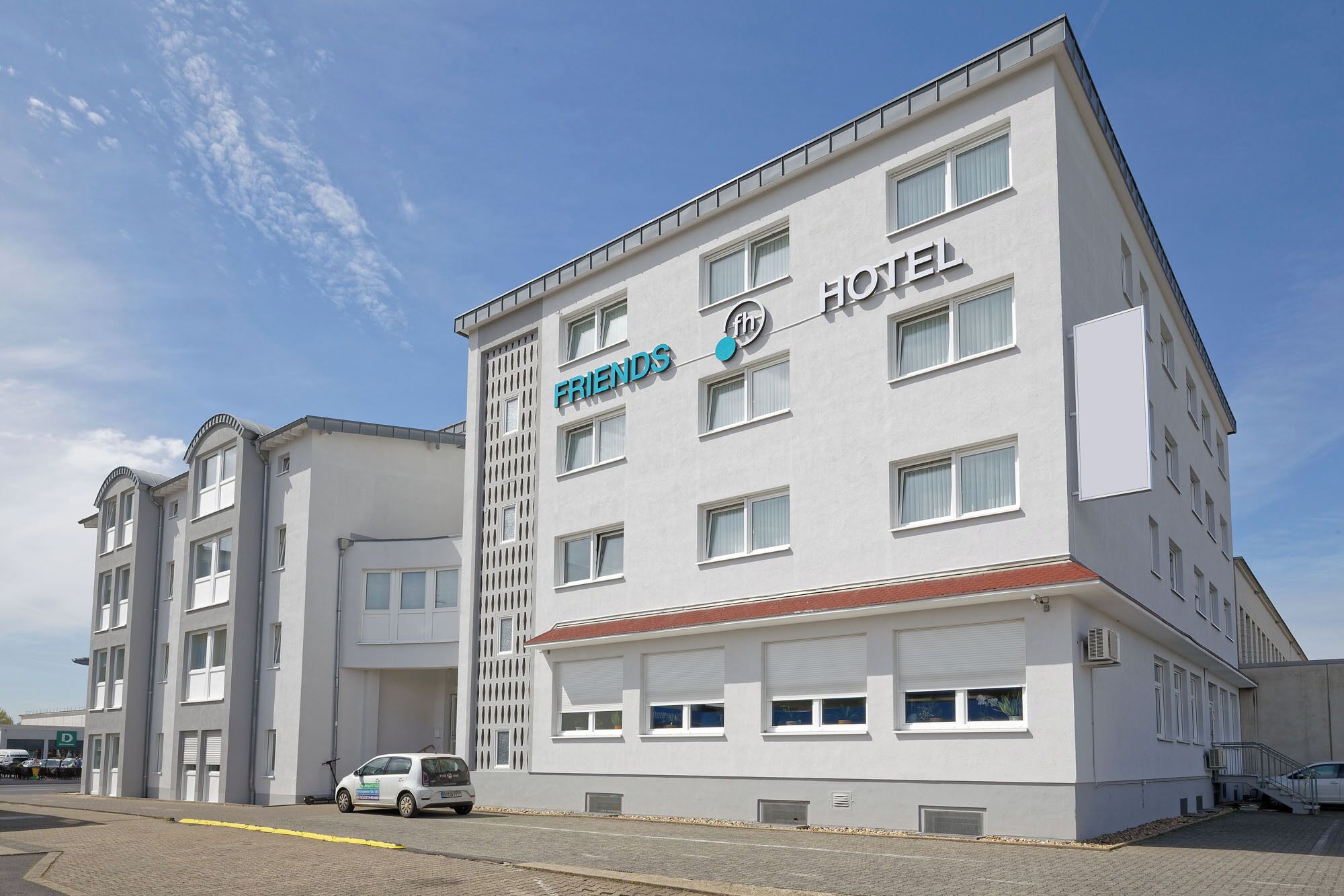 Un hôtel moderne, reconnaissable à son enseigne où l’on peut lire « FRIENDS HOTEL » et à son logo qui indique qu’il fait partie de la chaîne hôtelière « FRIENDS ».