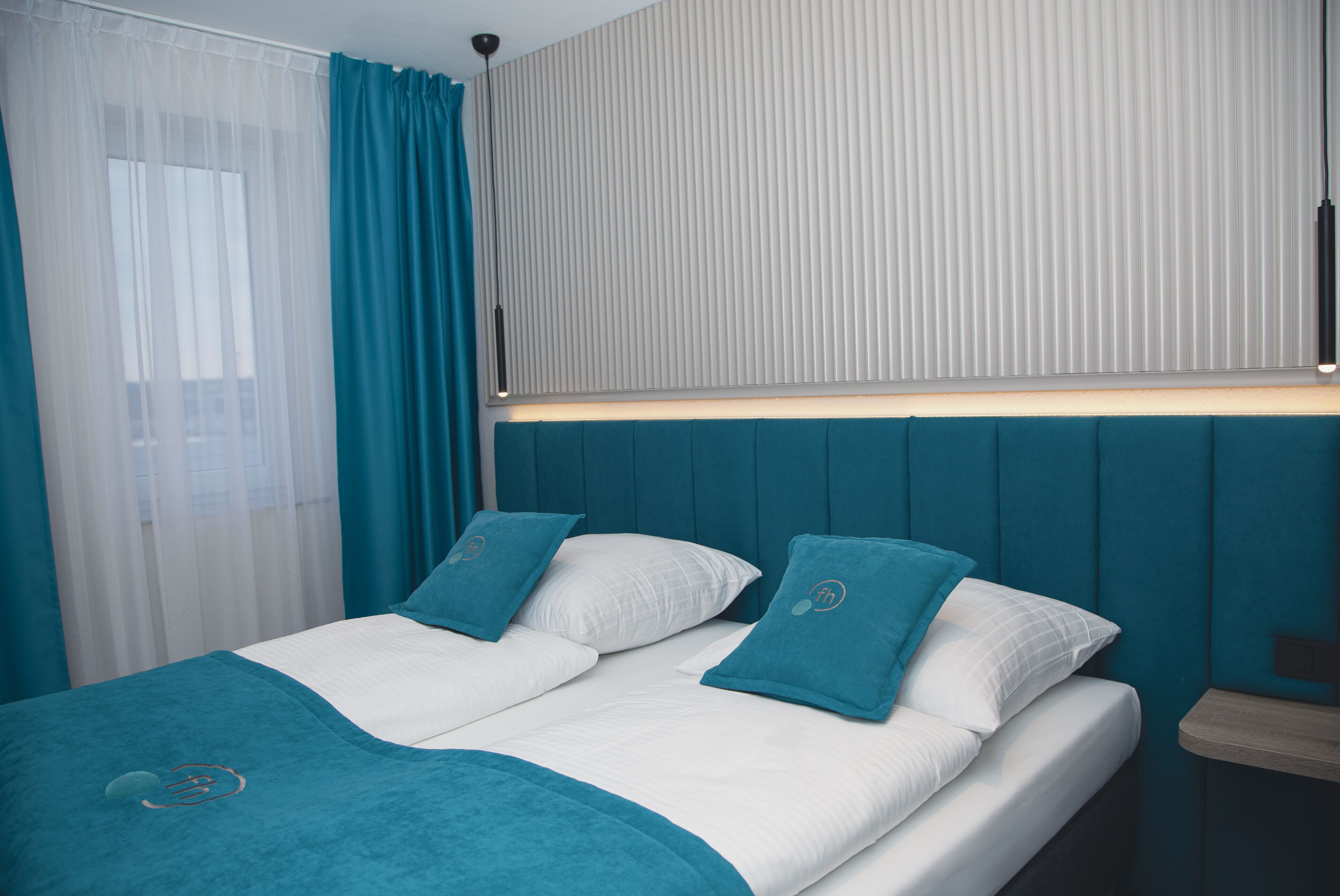 A hotel room with a bed, curtains, and a window with blinds.