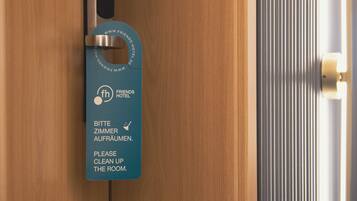 Una puerta de madera con un picaporte de metal y un letrero azul que dice 'Por favor, ordenen la habitación'.