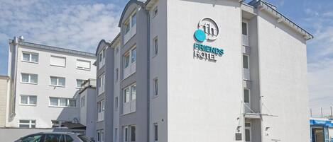 A Friends Hotel building with a white facade, a visible entrance, and a SuperWash store adjacent to it.