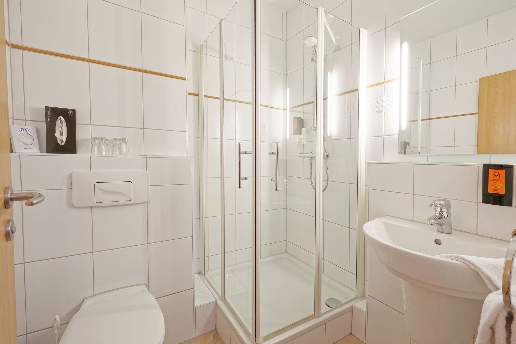 Ein modernes Badezimmer mit Duschkabine aus Glas, einem weißen Waschbecken und einer Toilette.