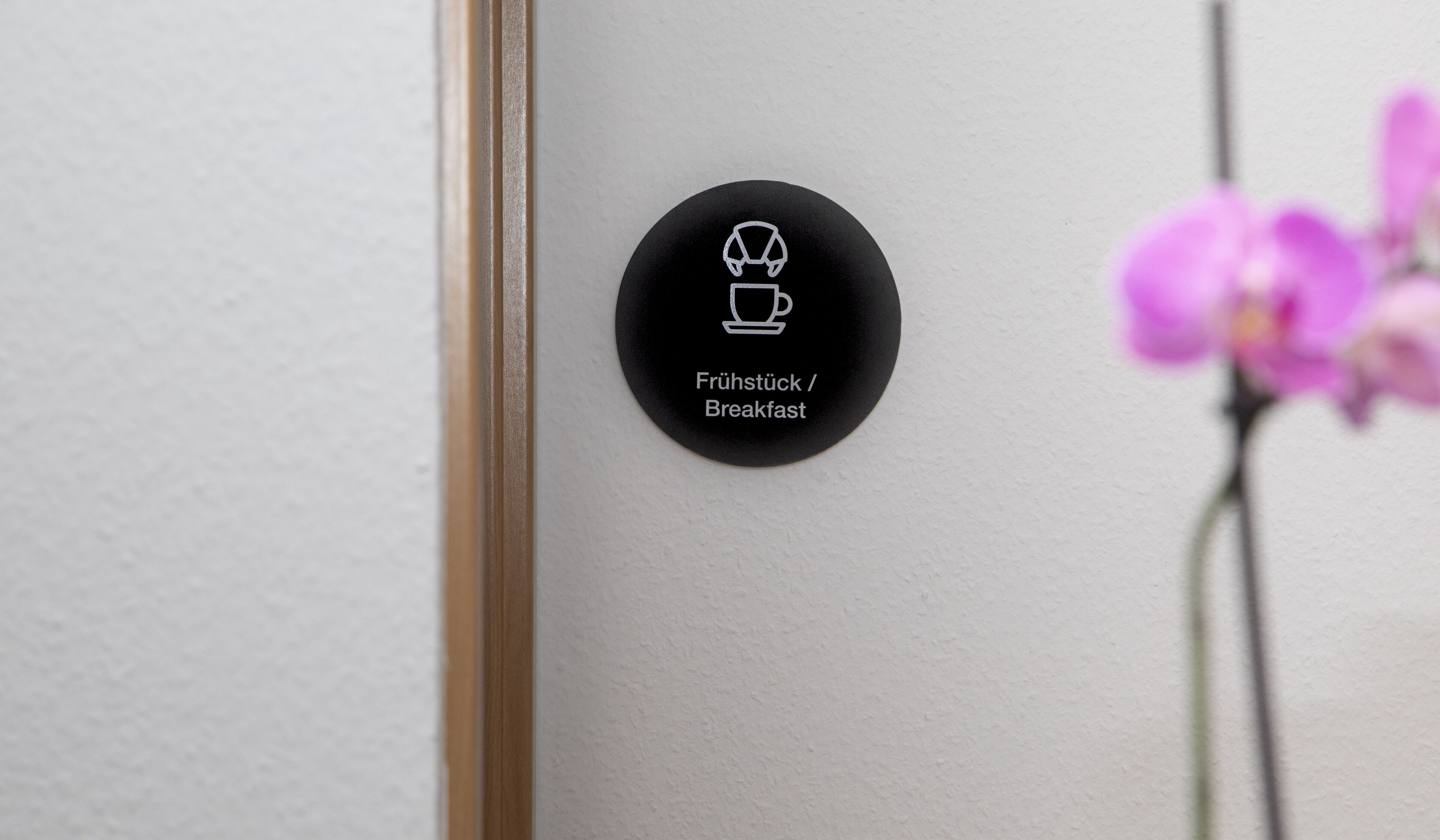 A black circular sign with white icons and text indicating a breakfast area.
