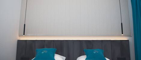 Een hotelkamer met een bed, een hoofdbord en een raam met zonwering.
