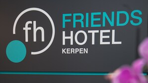 A logo with 'fh' and 'friends hotel kerpen' text, a teal stripe, and a blurred purple flower. - Friends Hotel Kerpen (Kerpen)