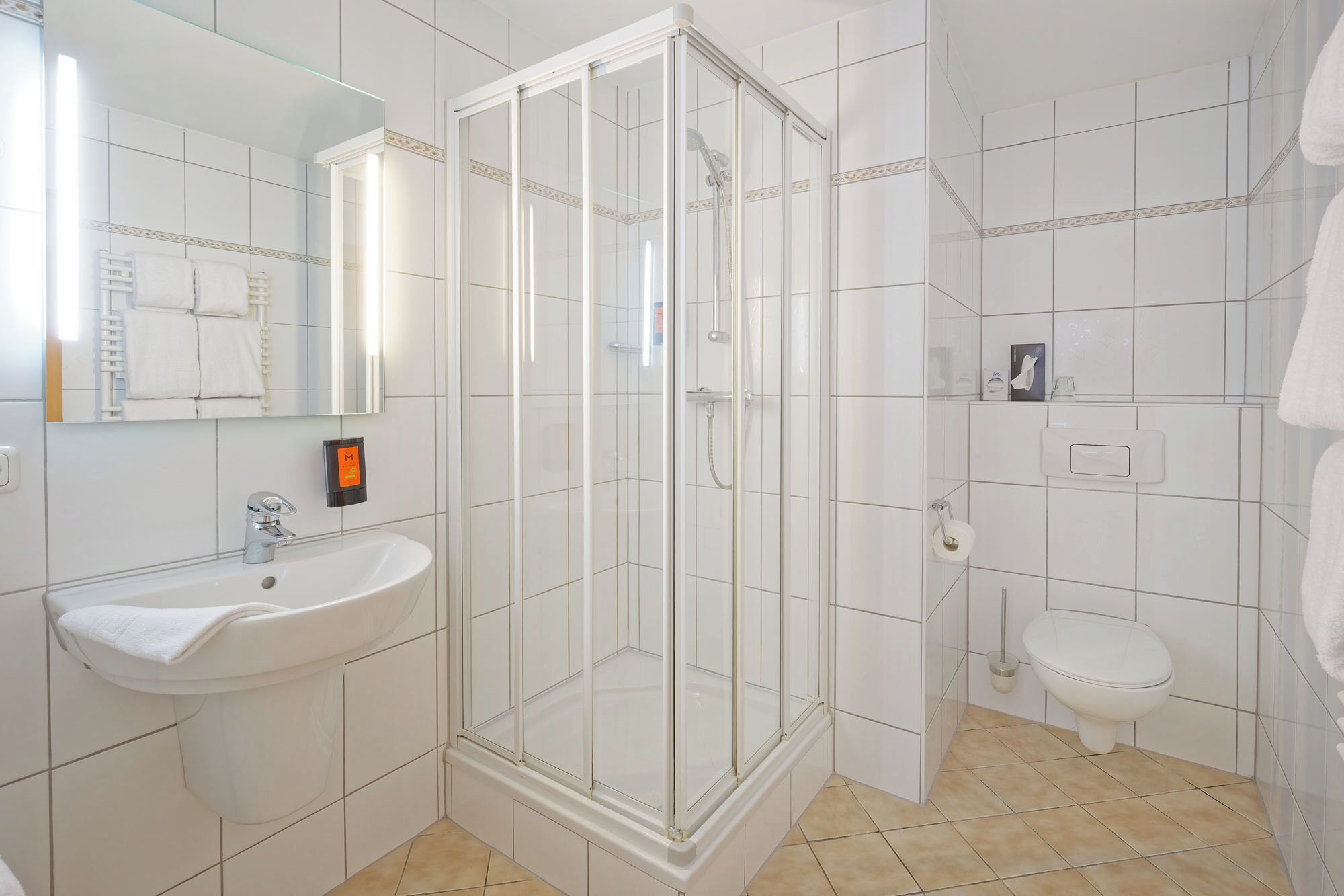 A bathroom with a glass-enclosed shower, a white sink, and a toilet.
