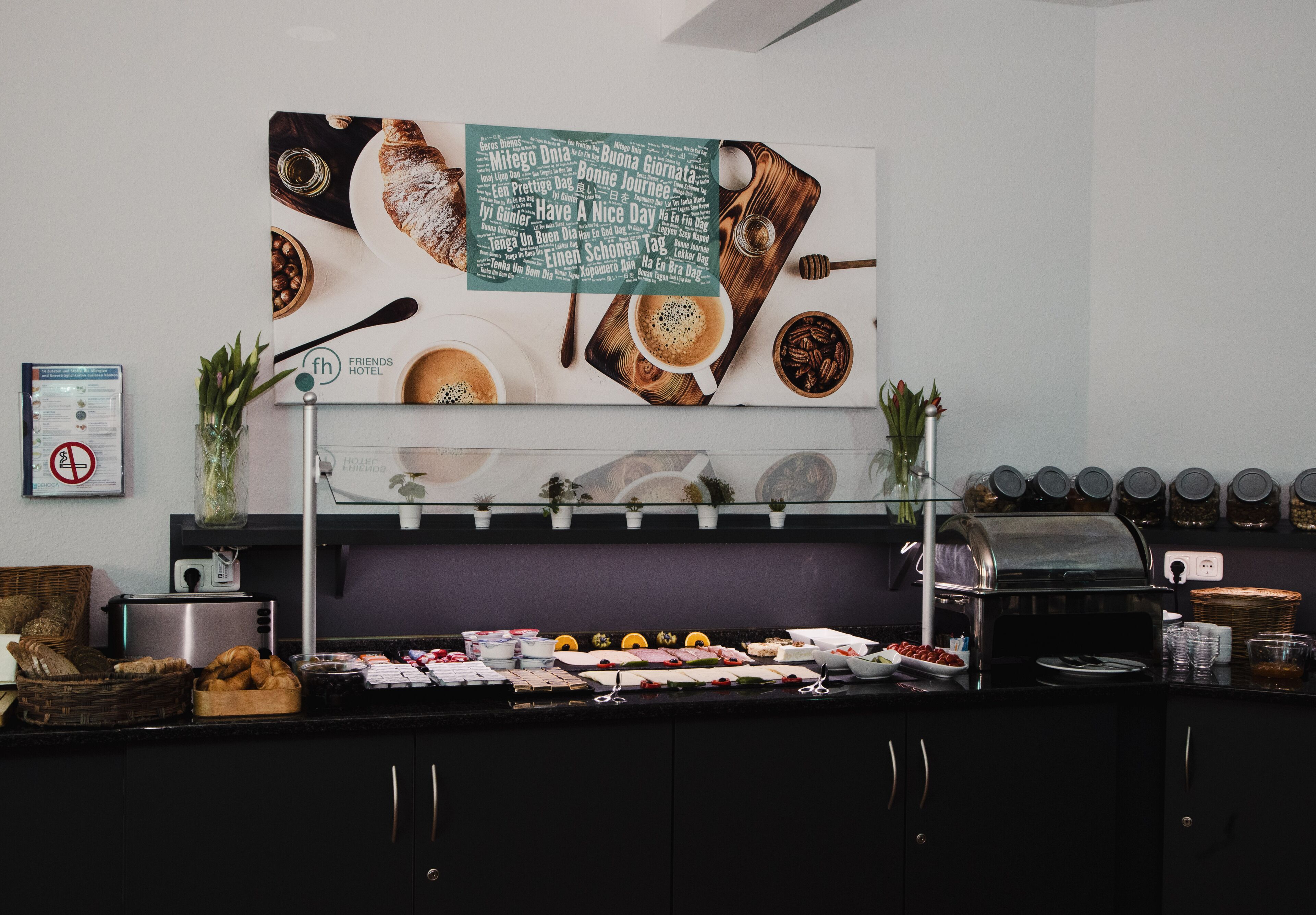 A breakfast buffet with various food items, a coffee machine, and a sign with positive messages.