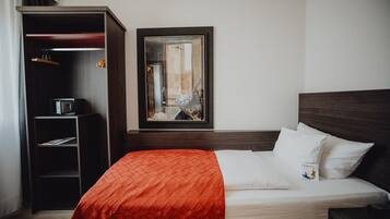 Una habitación de hotel con cama, armario y un cuadro en la pared.