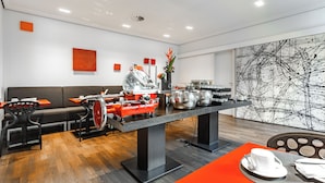 Un restaurant modern amb una taula central, zona de seients i una gran obra d'art abstracta a la paret.