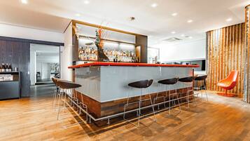 Uma área de bar moderna com balcão de madeira, vários bancos e uma planta decorativa.