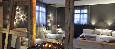 Una sala de estar moderna con chimenea, vigas de madera y una zona de estar acogedora.
