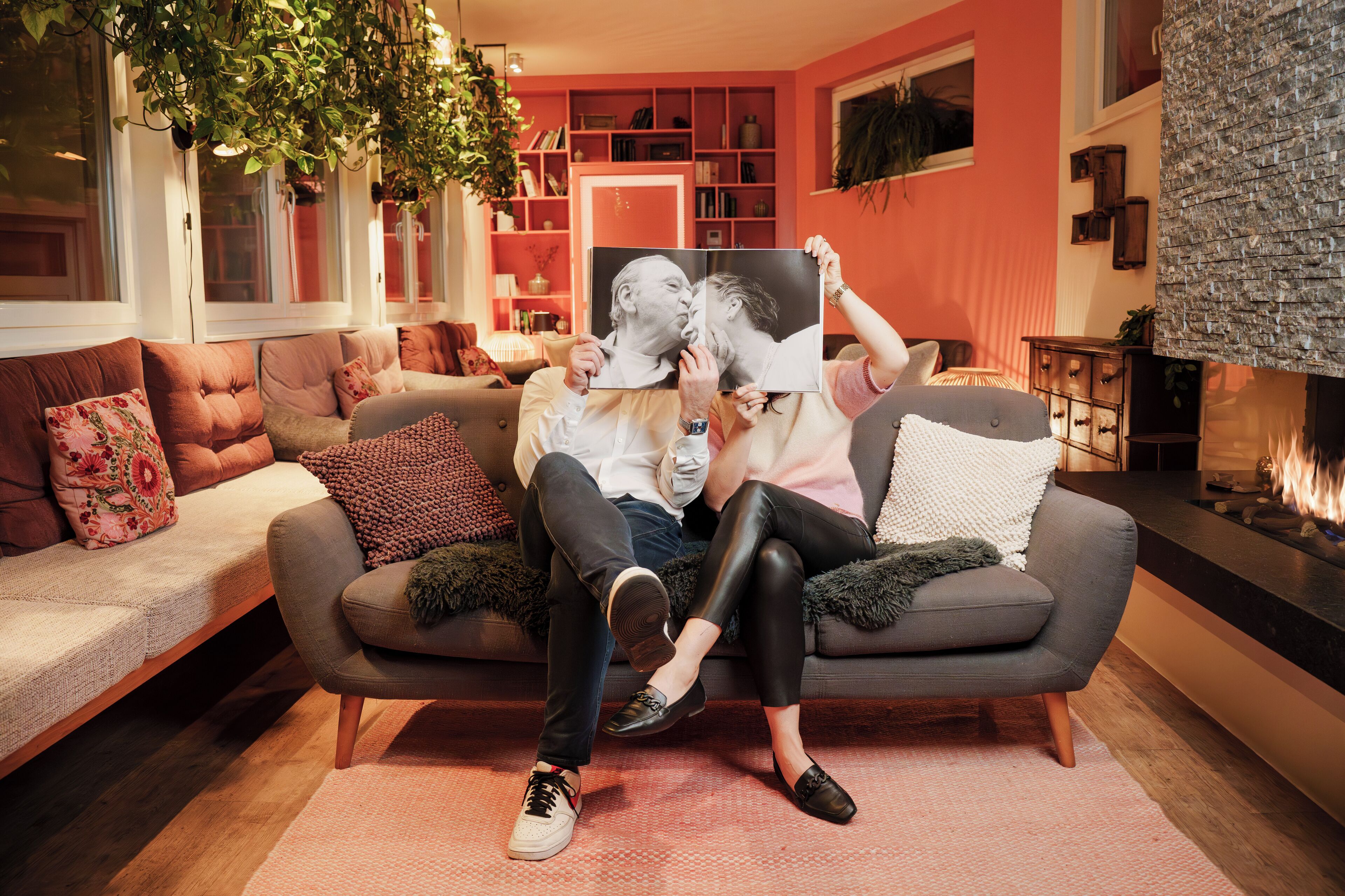 Ein gemütliches Wohnzimmer mit grauem Sofa, Kamin und Bücherregal.