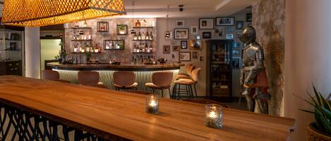 Zona de bar con barra de madera, varios taburetes y una lámpara colgante decorativa.
