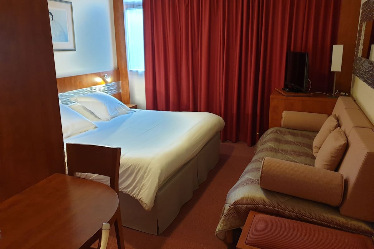 Una habitación de hotel con cama, sofá, escritorio y televisión.