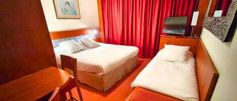 A hotel room with two beds, a desk, a chair, a TV, and a red curtain.