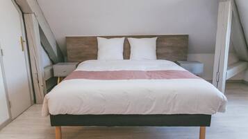 Une chambre à coucher avec un lit, deux tables de chevet et une petite table d’appoint.