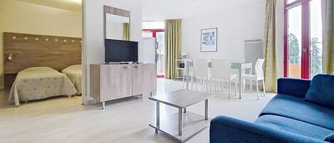Une chambre d’hôtel équipée d’un lit, d’une télévision, d’un bureau, d’une chaise, d’un canapé et d’une table à manger.