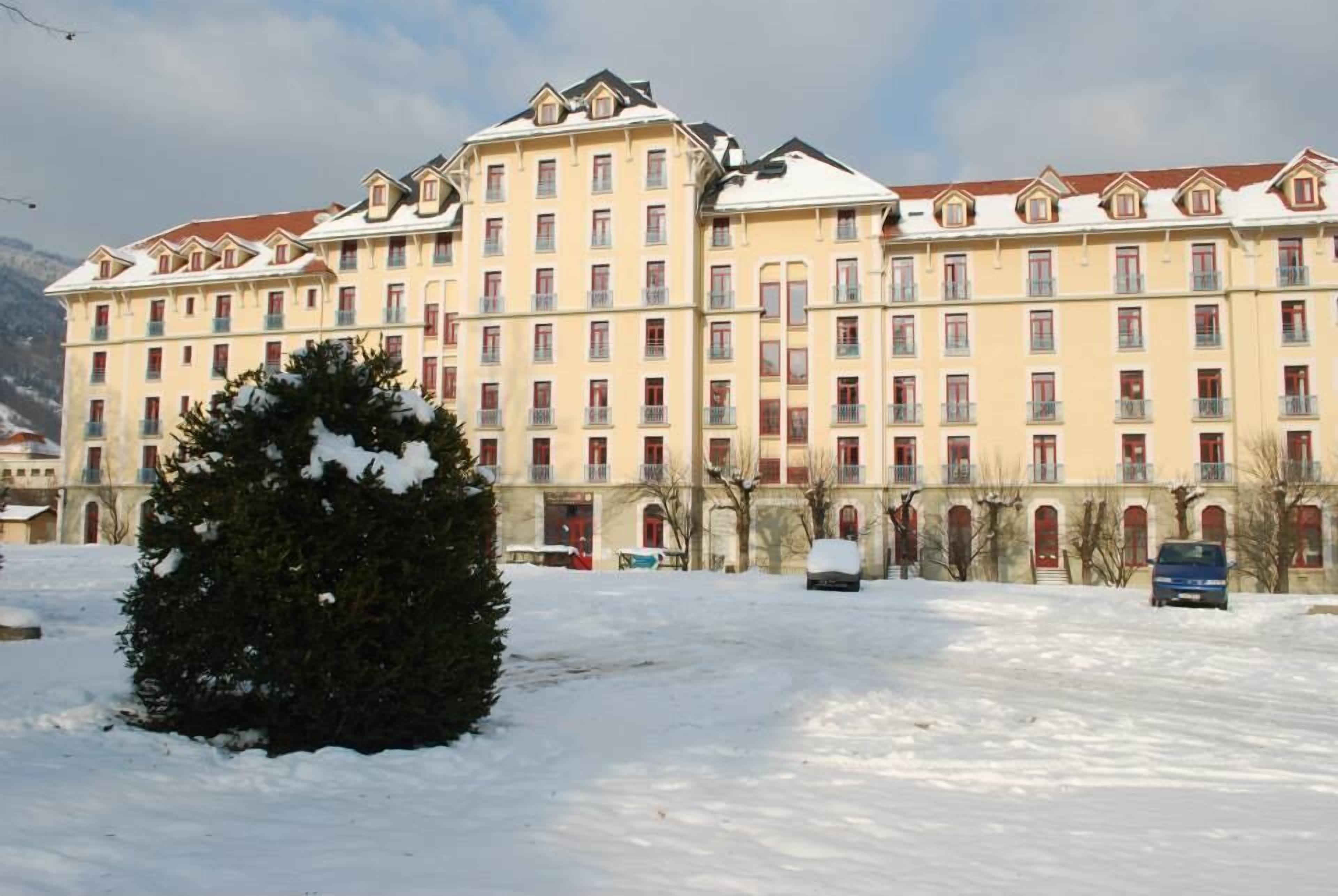 A multi-story hotel with a symmetrical facade, balconies, and a snow-covered landscape.