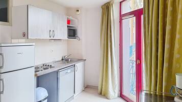 A compact kitchen with a refrigerator, microwave, sink, and stove.