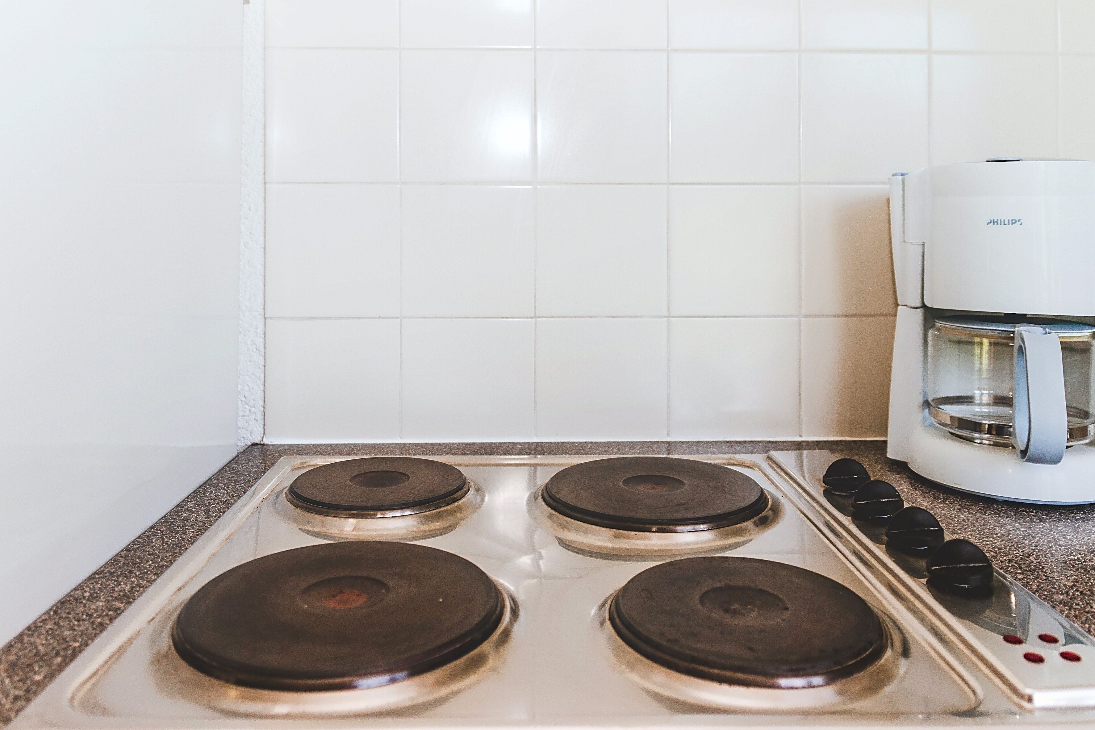 Een keuken met een wit fornuis, vier branders en een koffiezetapparaat.
