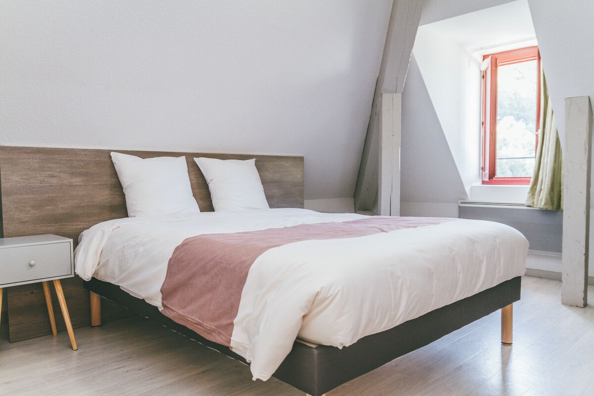 A modern bedroom with a wooden headboard, a white bedspread, and a wooden nightstand.