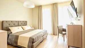 A hotel room with a large bed, a desk, and a chair. - Hotel Atlantico (Forte dei Marmi)