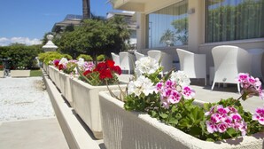 A hotel patio with outdoor seating and flower planters. - Hotel Atlantico (Forte dei Marmi)