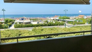 A balcony with a view of a beach and marina, including boats and buildings. - Hotel Atlantico (Forte dei Marmi)