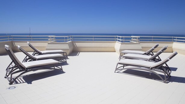 A rooftop terrace with two sun loungers and a table, overlooking a clear blue sea. - Hotel Atlantico (Forte dei Marmi)