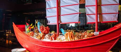 A red boat-shaped buffet with various seafood dishes and condiments.