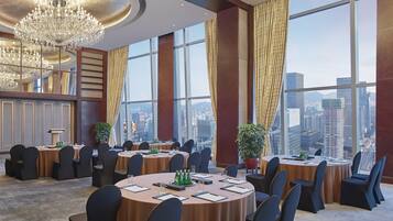 A conference room with multiple tables, chairs, and a large chandelier.