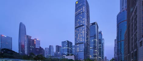 A cityscape with modern high-rise buildings, a well-maintained road with light trails, and a clear sky.