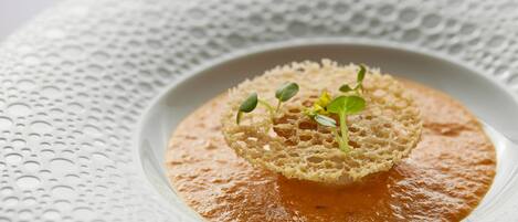 A bowl of soup with a piece of bread on top, placed on a textured white plate.