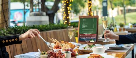 A dining table with a variety of food items, including a bowl of olives, a plate of pasta, and a glass of wine.