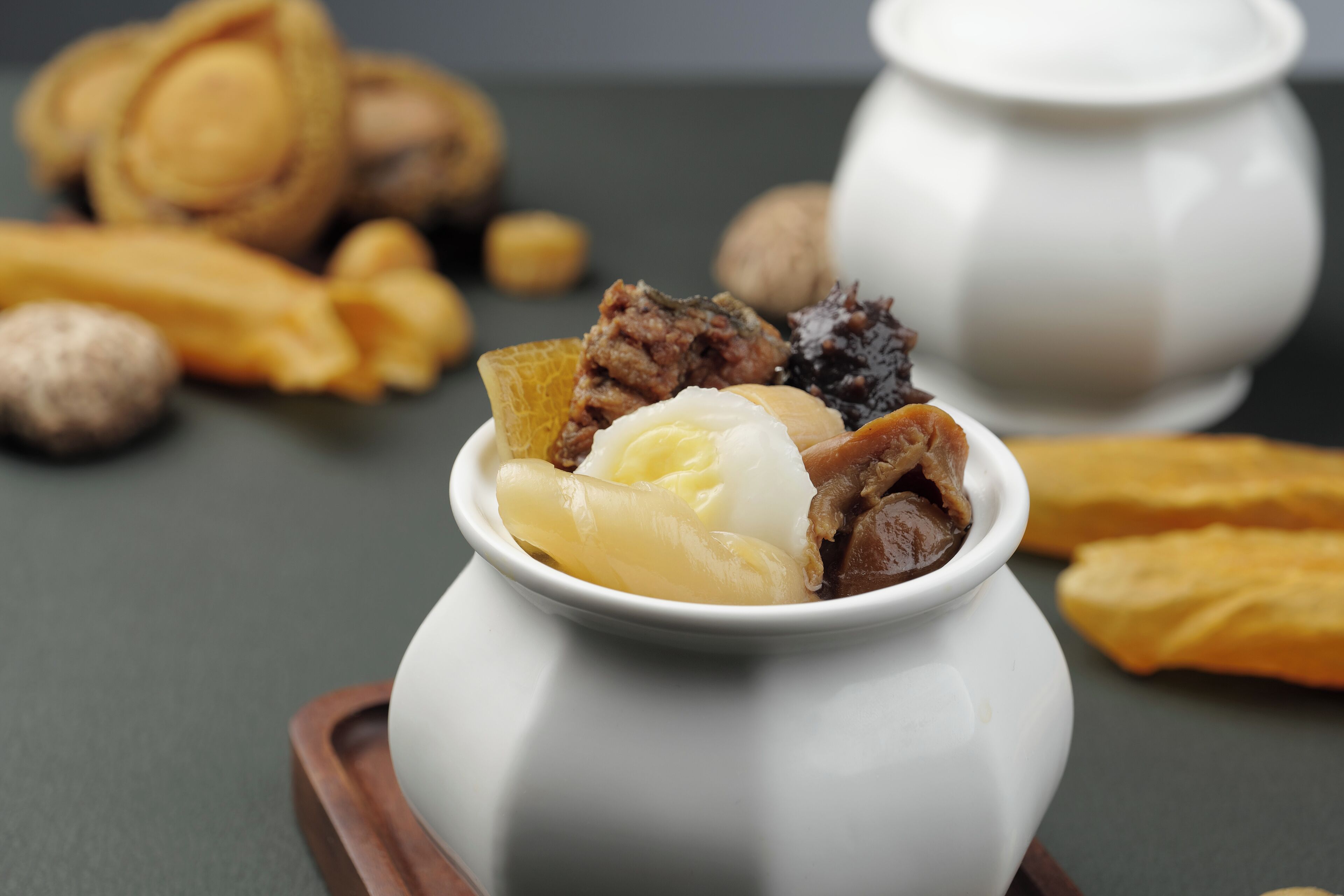 A white ceramic bowl containing various food items on a wooden tray.