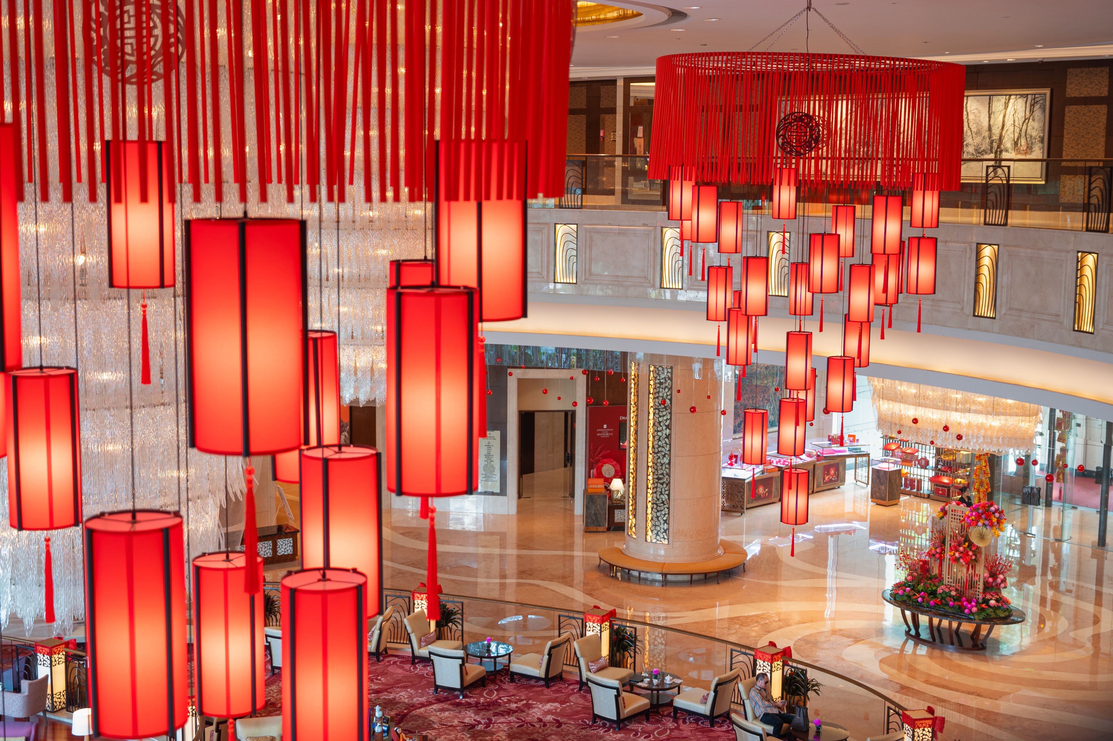 A spacious lobby with red hanging lanterns, a central column, and seating areas.