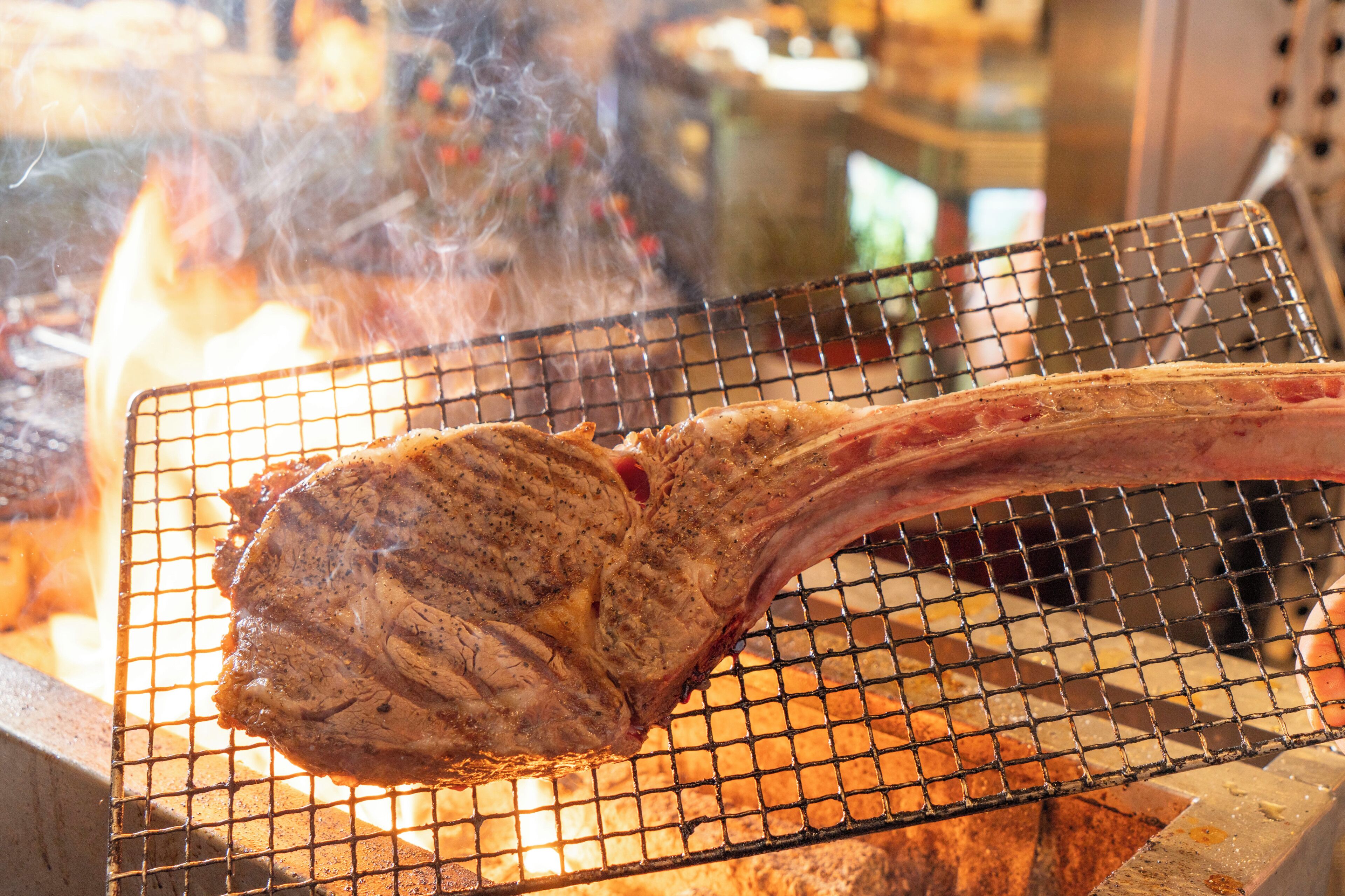 A large piece of meat being grilled on a wire rack over an open flame.