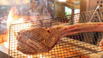 A large piece of meat being grilled on a wire rack over an open flame.