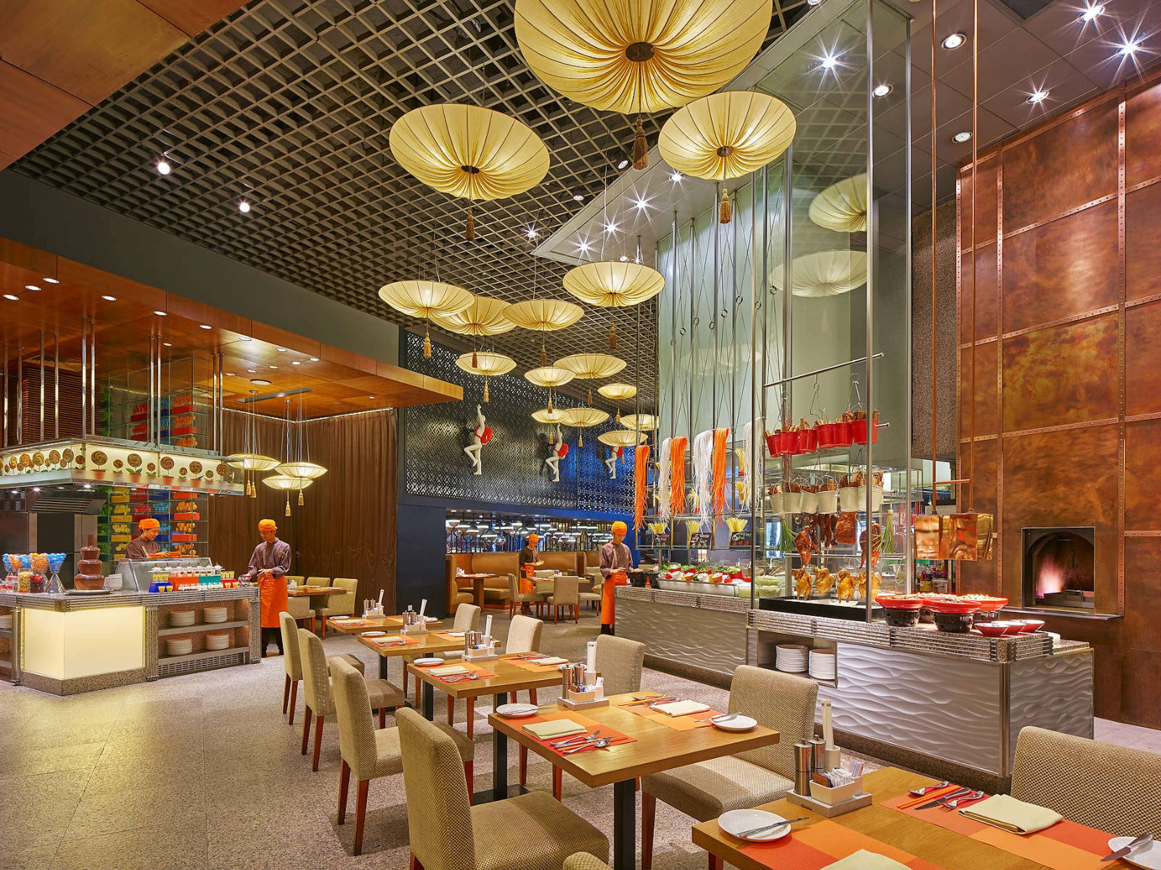 A modern restaurant with high ceilings, hanging paper lanterns, and a central bar area.