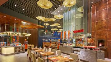 A modern restaurant with high ceilings, hanging paper lanterns, and a central bar area.