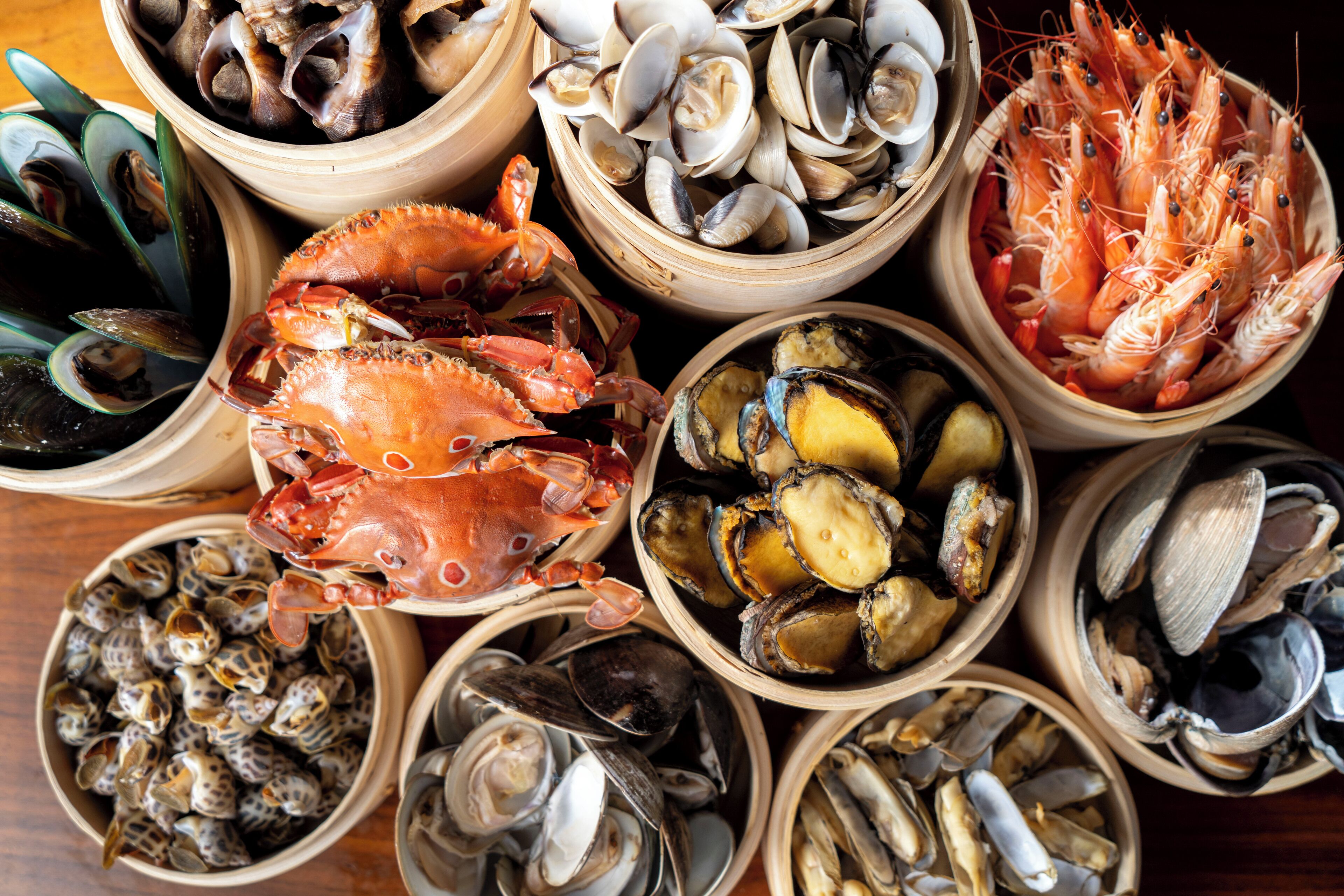 Mariscos variados dispuestos en cuencos de madera.